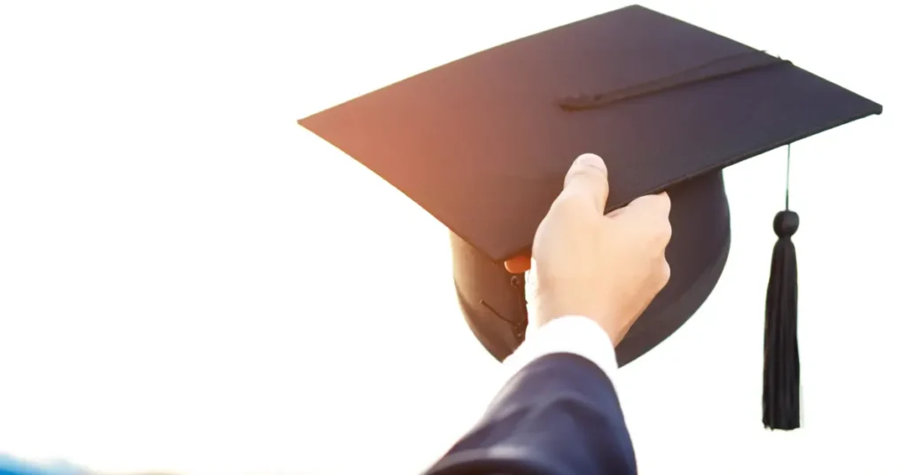 A graduation cap held in a hand, signifying academic achievement and potential future success. Budget Analyst Jobs