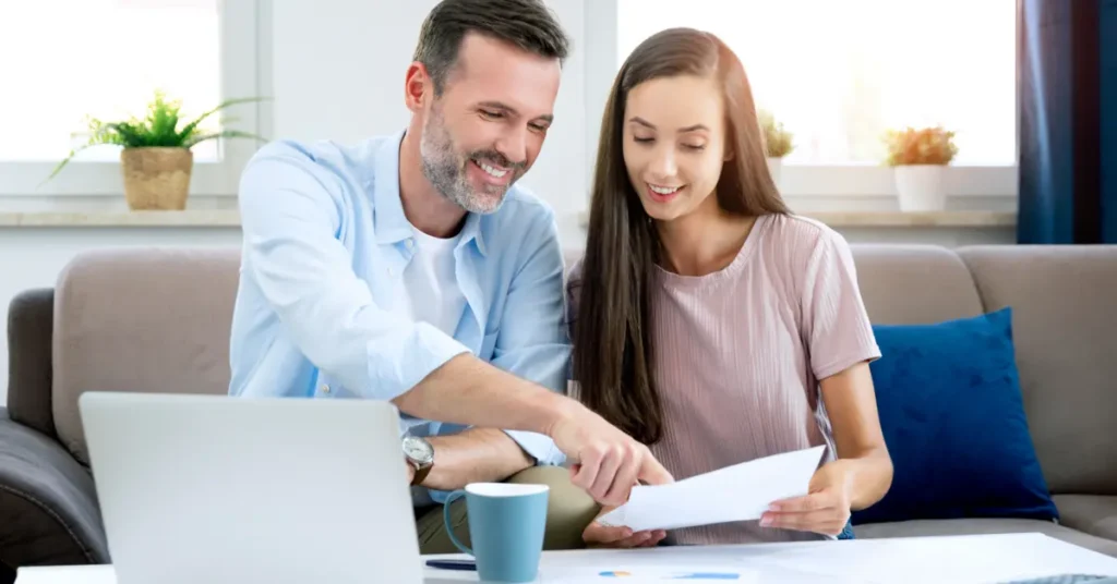 A smiling couple reviewing financial documents, reflecting a positive approach to household budgeting. Budgeting for Dummies