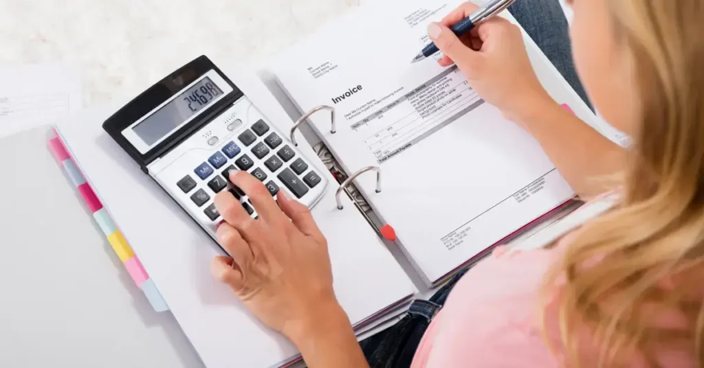 A person calculating finances or an invoice, representing budgeting or accounting tasks. She is doing her regulary work on her budgeting journal.