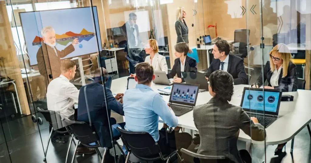 A business meeting with the finance director and participants around a table with laptops.  