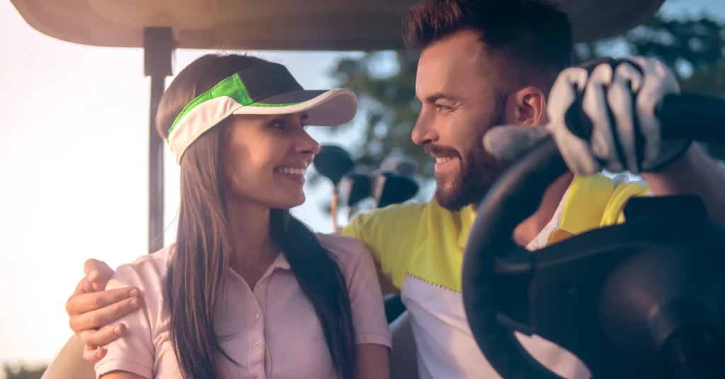 A young couple, with the man driving, sharing a moment in a golf cart.