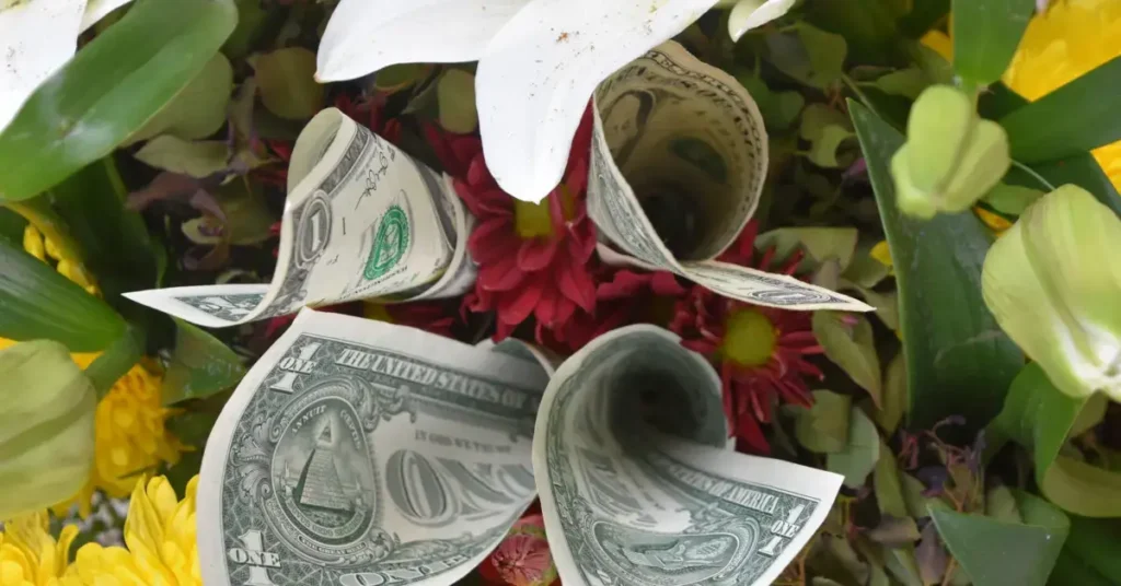 Dollar bills folded into flower-like shapes placed within a bouquet of real flowers. Different way of money rose bouquets