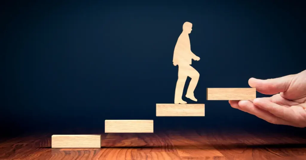 A conceptual image of a wooden figure climbing stairs made of wooden blocks visualizing business development.