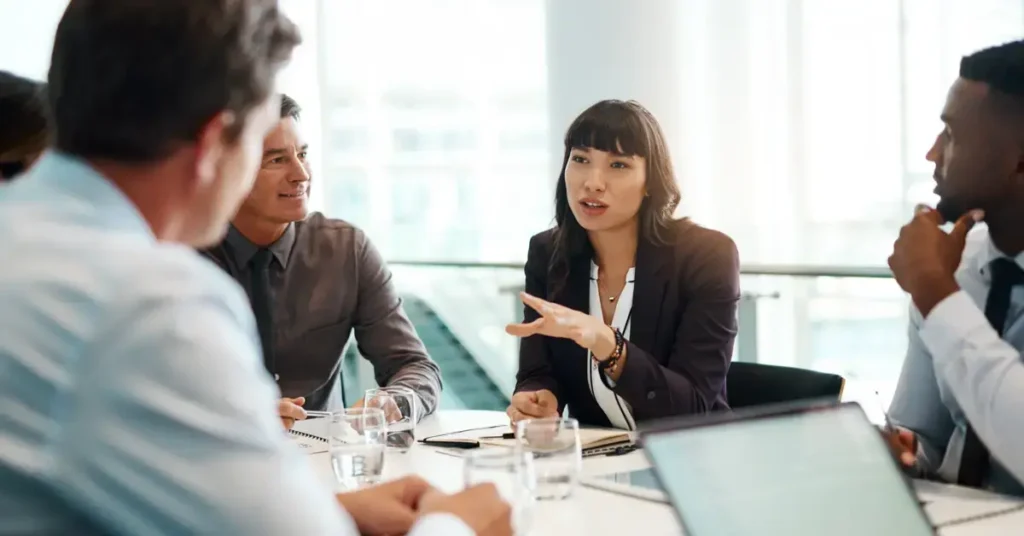 A corporate setting with a diverse group of professionals engaged in a discussion. Communicating with stakeholder is part of strategic finance