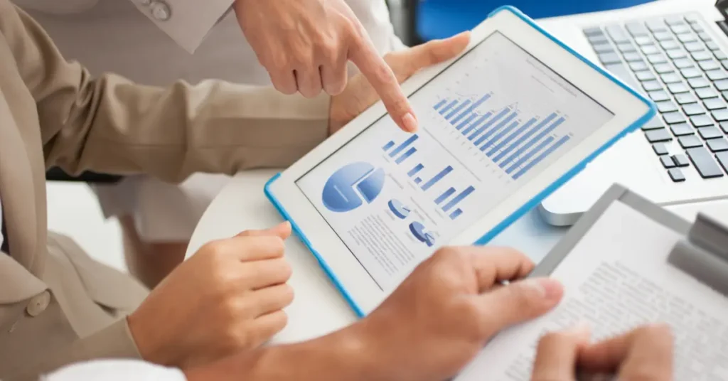 Two individuals examining financial data on a digital tablet.