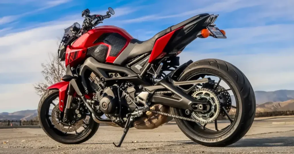 A parked red and black motorcycle outdoors with a scenic backdrop. Might be a yamaha